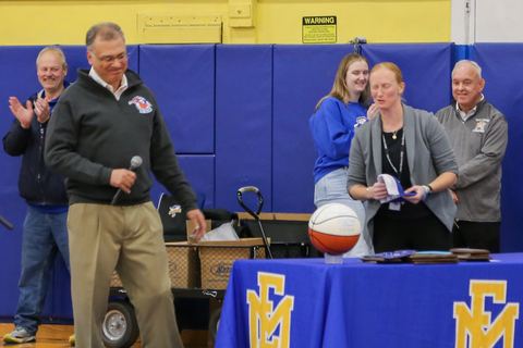 Coaches and staff presenting an award at a table in the school gymnasium
