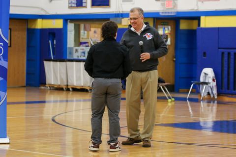 A coach shaking hands with a player on the gym floor
