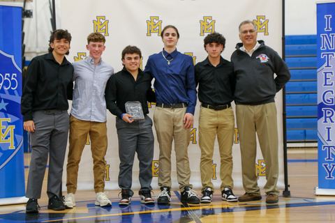 Award recipients lined up with a coach in front of the school banners