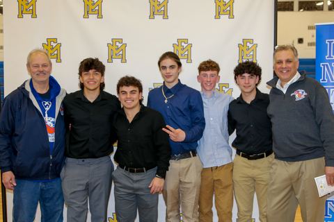 Players and two coaches together in front of the East Meadow backdrop