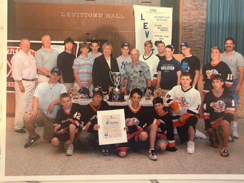 Team, coaches and officials gathered with a trophy and a framed award at Levittown Hall