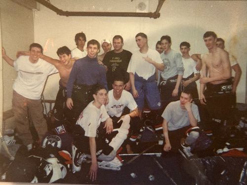 Players celebrating in a locker room after a win, gear scattered across the floor