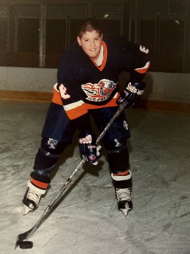 A player in a dark Ice Falcons jersey posed on the ice with his stick