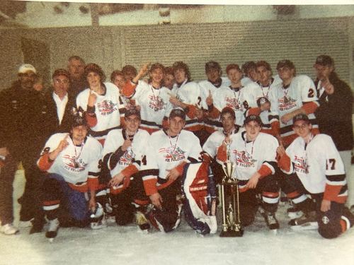 Team in white jerseys gathered around a large trophy on the ice after a championship win